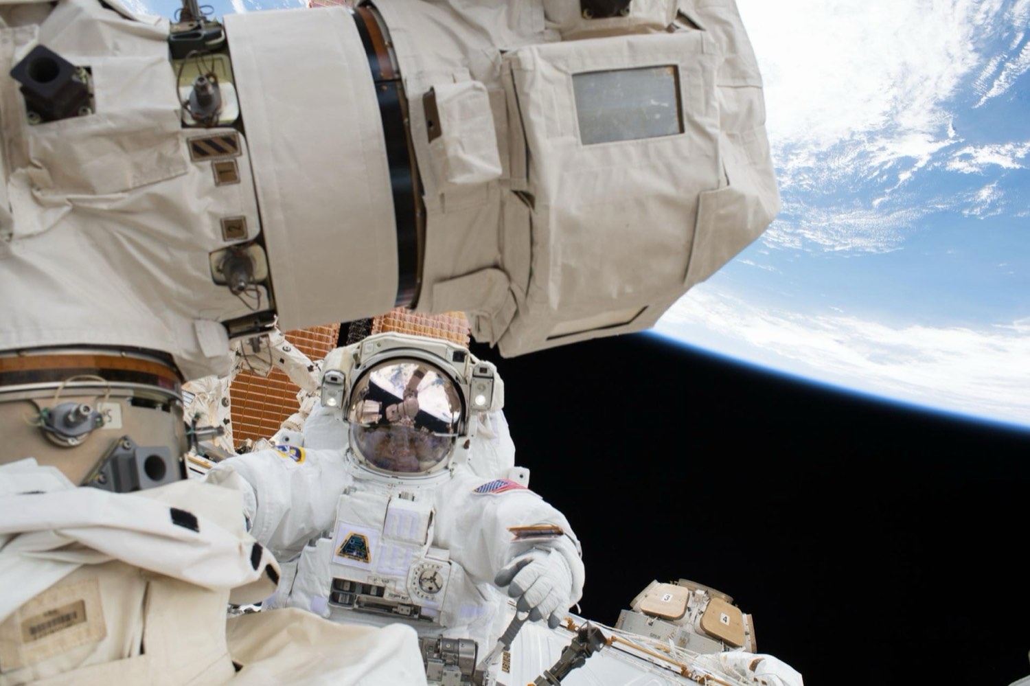 Astronauta trabajando fuera de la Estación Espacial Internacional, con la Tierra de fondo.